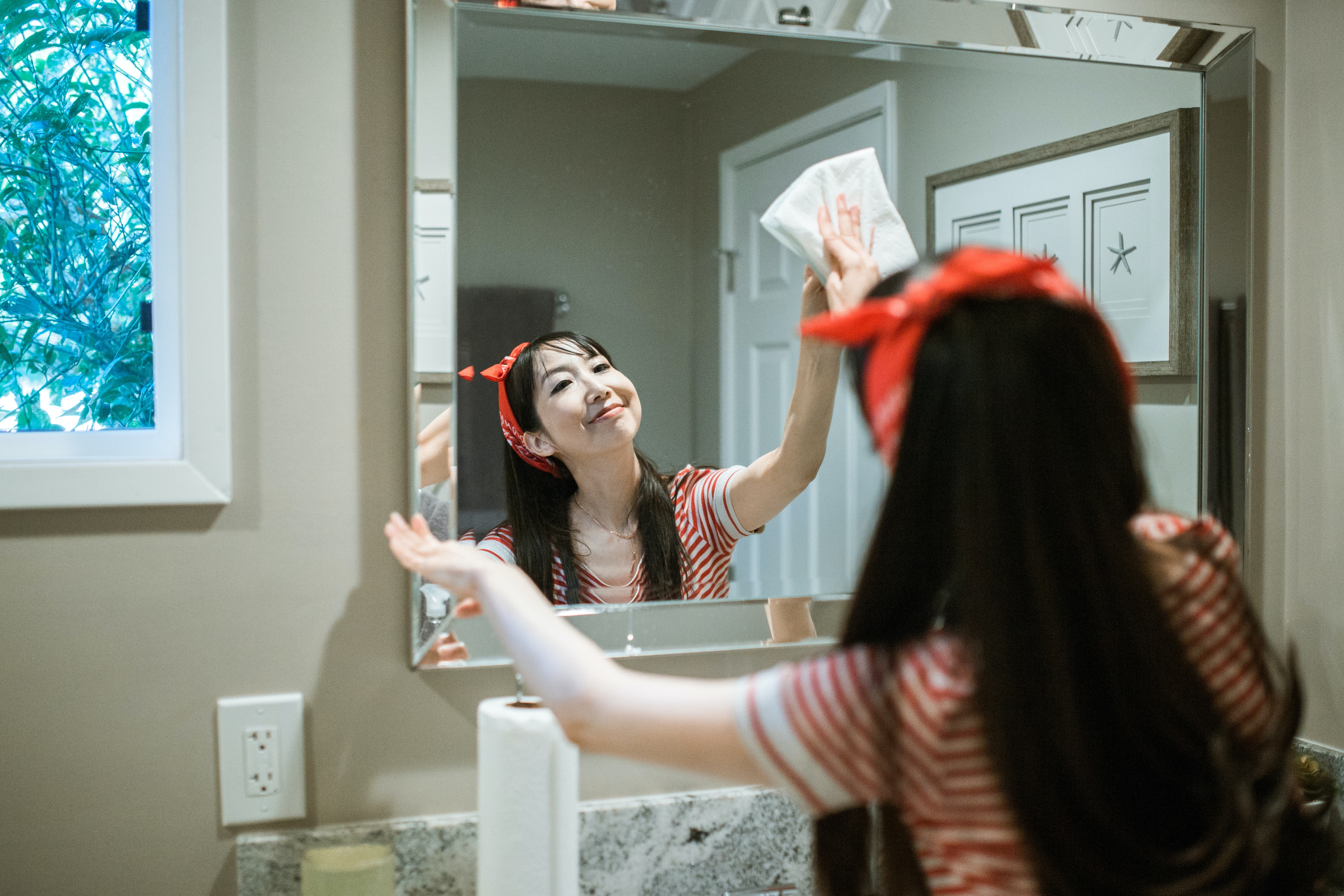 woman in black and white striped shirt wiping the mirror