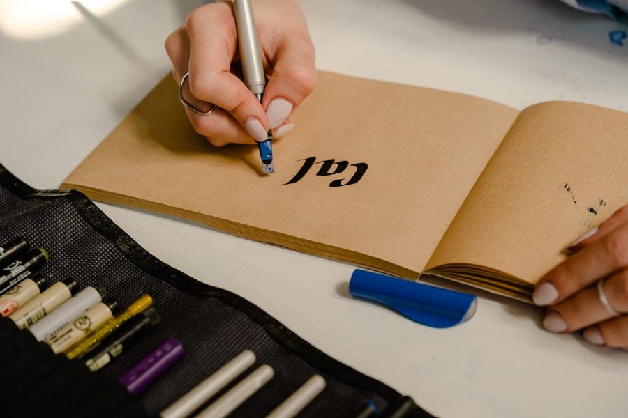A person with white nail polish doing calligraphy