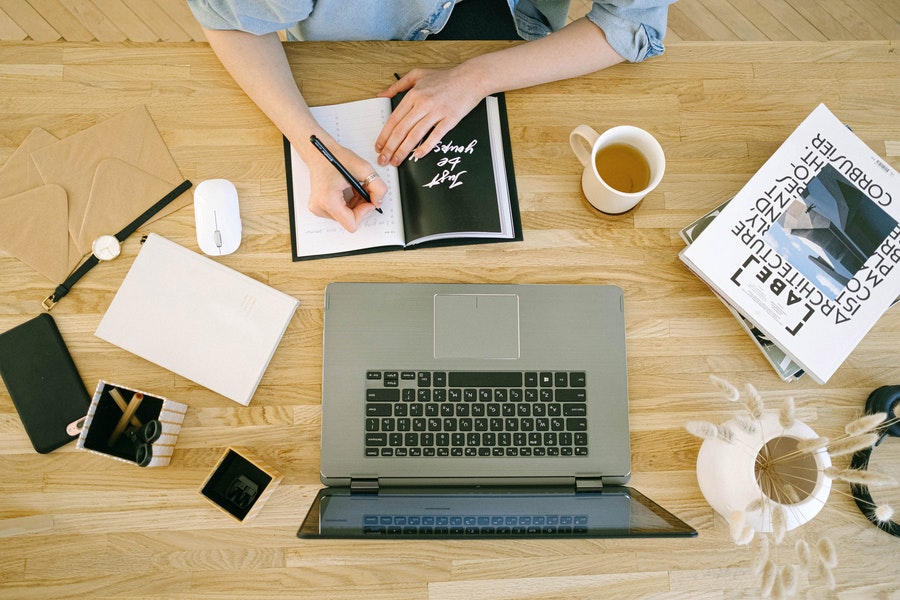 A woman writing on her journal infront of her laptop