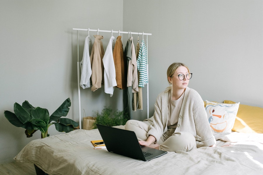 A girl sitting on a bed while working on her laptop