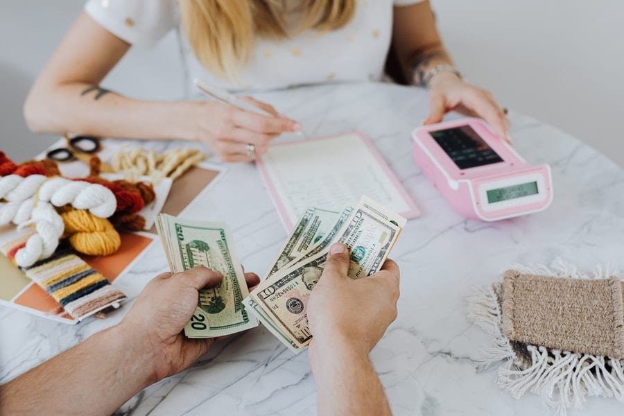 Person counting dollar on the table while the other one is calculating