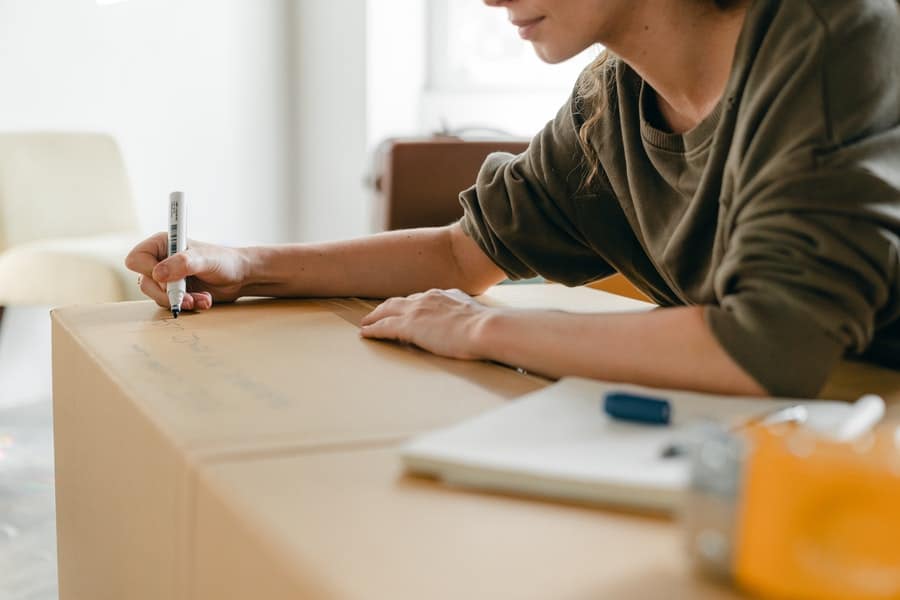 A woman writing on a box using a marker