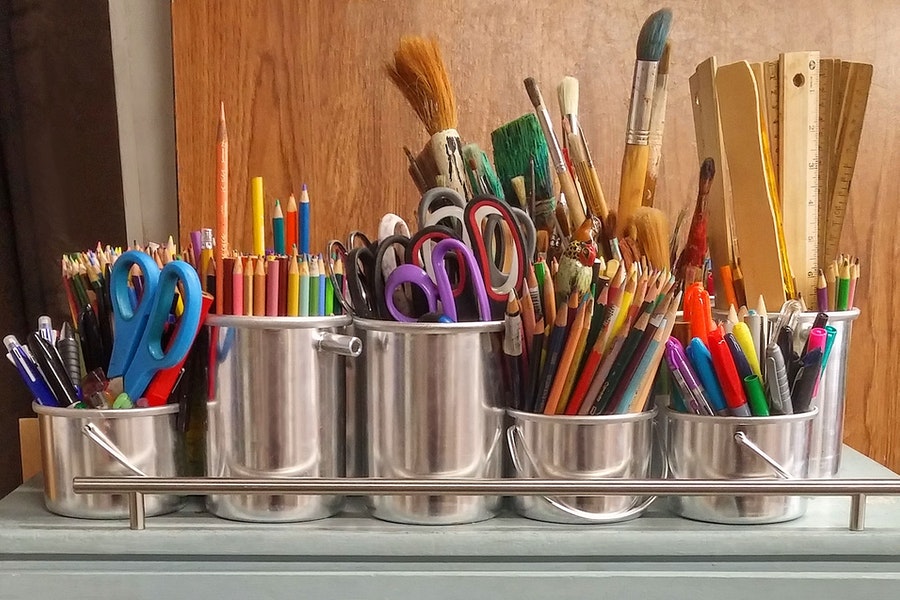 pencils and other art supplies in a stainless steel bucket