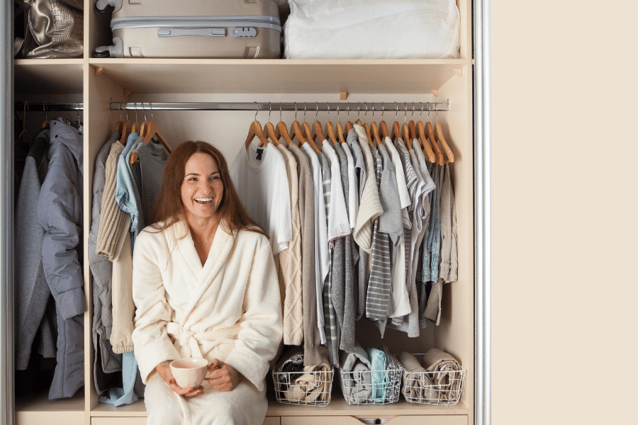 Woman smiling while sitting in her organized closet