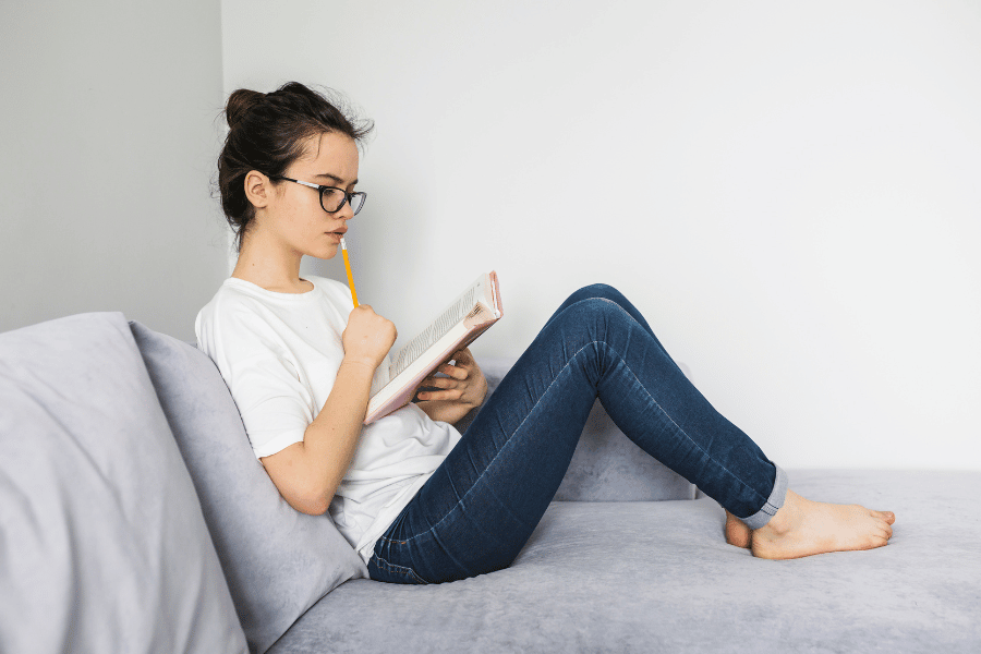 A lady sitting on a sofa with a pencil and notebook